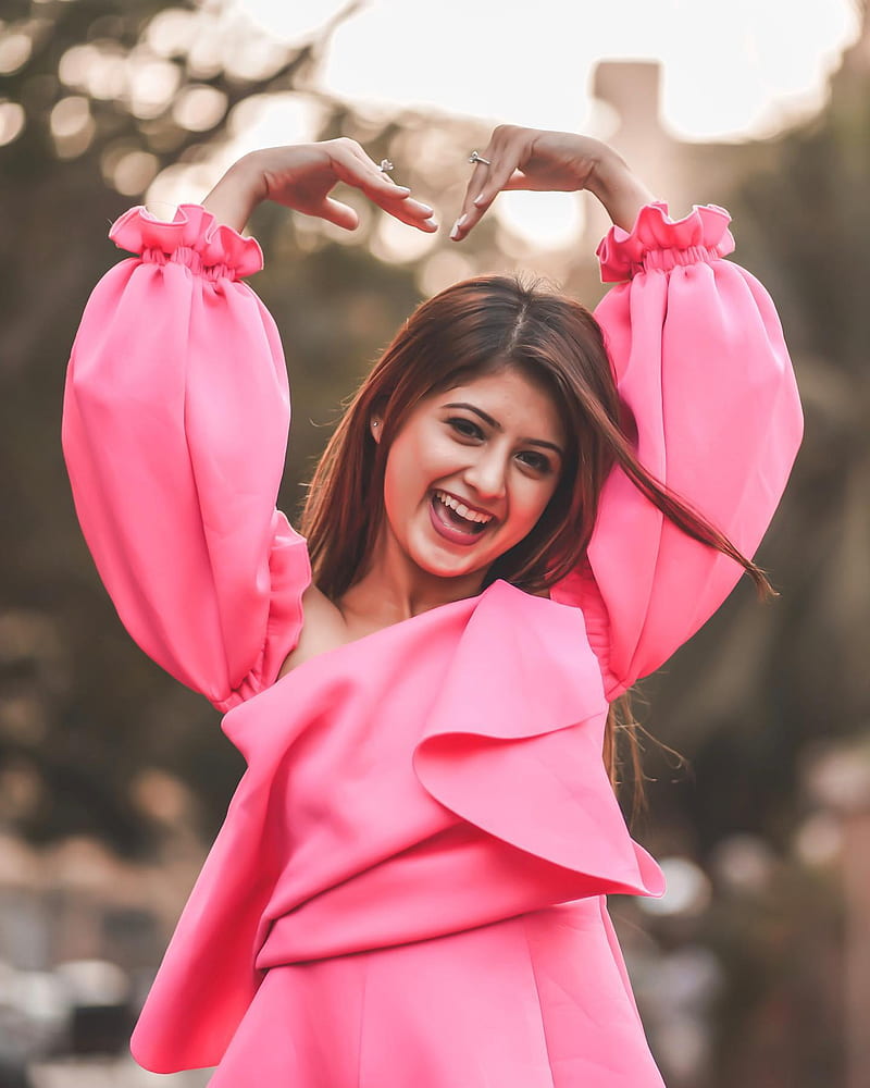 Arishfa Khan smiling and making a heart with her hands in a bright pink dress