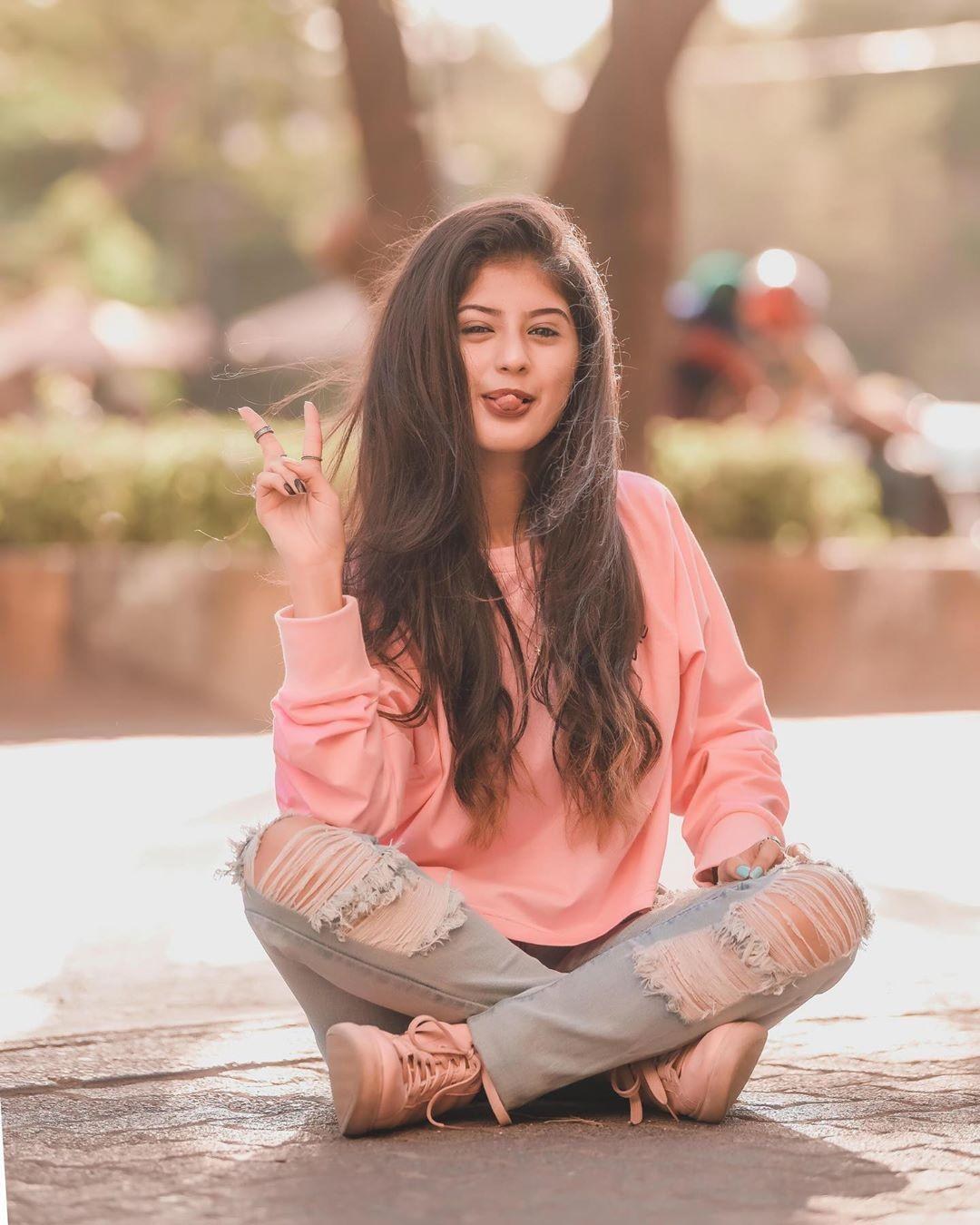 Arishfa Khan posing playfully outdoors in a casual pink sweater